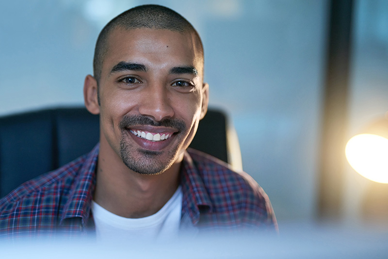 A person smiling at you while sitting on a desk.